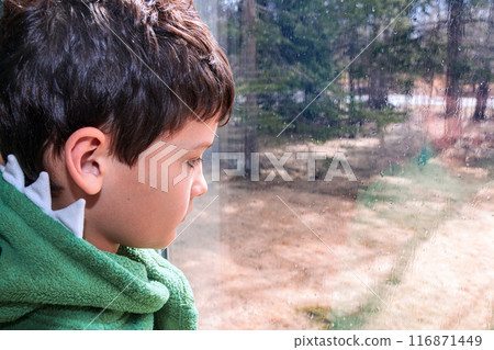 Boy is looking through the window with raindrops in rainy day. Boy is looking through the window with raindrops in rainy day. 116871449