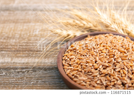Wheat in a plate on a wooden table and dry yellow ears. Wheat in a plate on a wooden table and dry yellow ears. 116871515