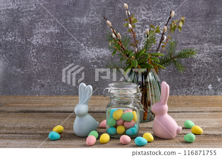 Easter bunnies, candy jar and willow bunch on the table. Easter bunnies, candy jar and willow bunch on the table. 116871755