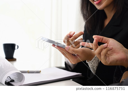 Cropped shot of smiling young businesswoman showing colleague something on smartphone 116875731