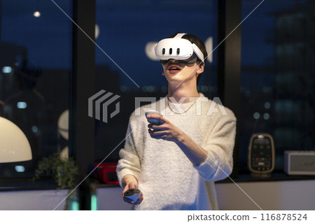 戴著 VR 護目鏡手持控制器的年輕人 116878524