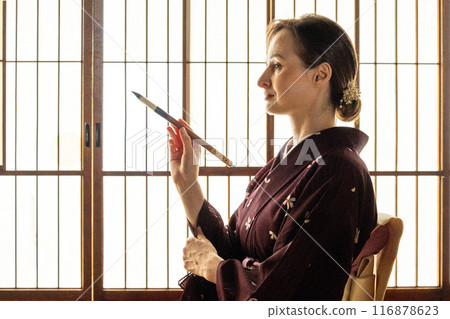 A foreign woman in a kimono practicing calligraphy A foreign woman in a kimono practicing calligraphy 116878623
