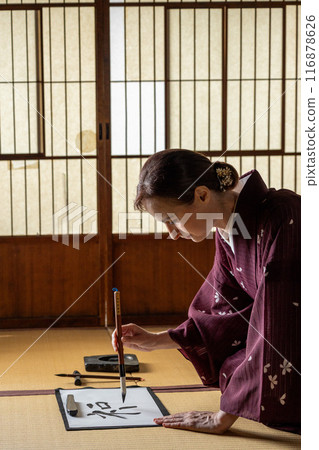 A foreign woman in a kimono practicing calligraphy A foreign woman in a kimono practicing calligraphy 116878626