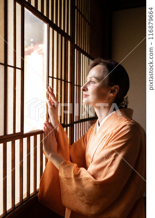 A foreign woman in a kimono sitting in front of a shoji screen 116879664
