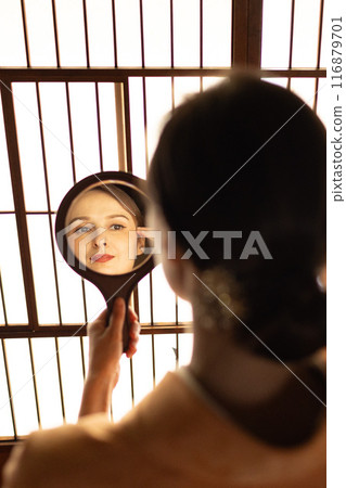 一位身穿和服的外國女子在障子屏風前看著手鏡 一位身穿和服的外國女子在障子屏風前看著手鏡 116879701