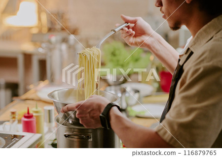 Young sous chef cooking handmade pasta in modern restaurant kitchen Young sous chef cooking handmade pasta in modern restaurant kitchen 116879765