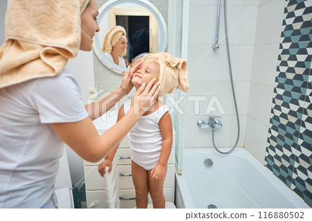 Happy mom puts a towel on girl kid head. Happy mom puts a towel on girl kid head. 116880502