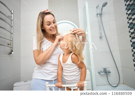 Young mother and daughter making curlers in a bathroom 116880509