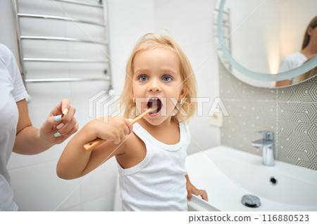 Morning routine, smiling happy child brushing teeth with toothbrush. 116880523