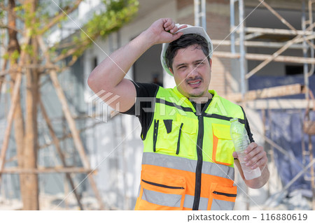 Hot Tired Thirsty Construction Worker Drinking Water on the Job Site 116880619