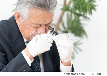 A man examining something with a magnifying glass 116880815