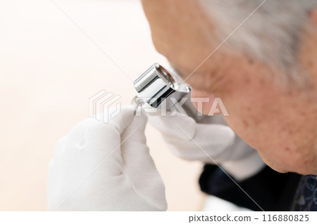 A man examining something with a magnifying glass 116880825