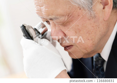 A man examining something with a magnifying glass 116880831