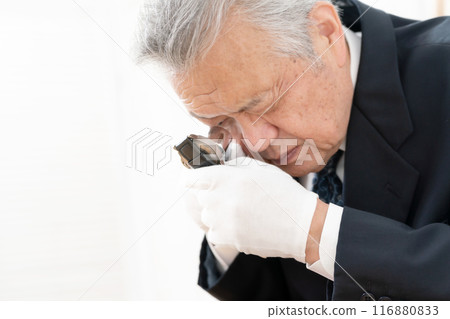 A man examining something with a magnifying glass 116880833