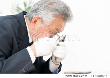 A man examining something with a magnifying glass 116880834