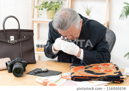 A man examining something with a magnifying glass 116880836