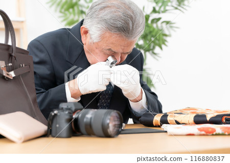 A man examining something with a magnifying glass A man examining something with a magnifying glass 116880837