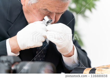 A man examining something with a magnifying glass A man examining something with a magnifying glass 116880838