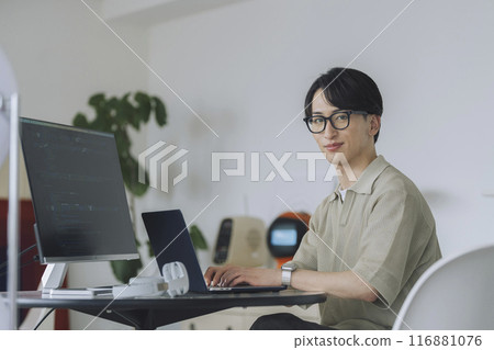 Young man wearing glasses working on a computer, looking at camera, portrait Young man wearing glasses working on a computer, looking at camera, portrait 116881076