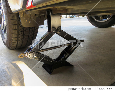 Lifting a car with a car jack to change a tire 116882336