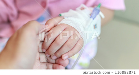 Mother holding child hand with saline IV solution in hospital 116882871