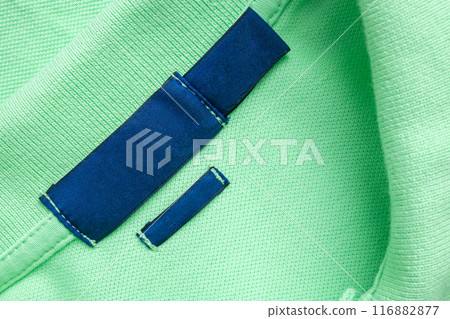 Blank blue laundry care clothes label on green shirt fabric texture background 116882877