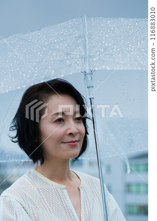 A middle-aged woman holding an umbrella in the pouring rain A middle-aged woman holding an umbrella in the pouring rain 116883010