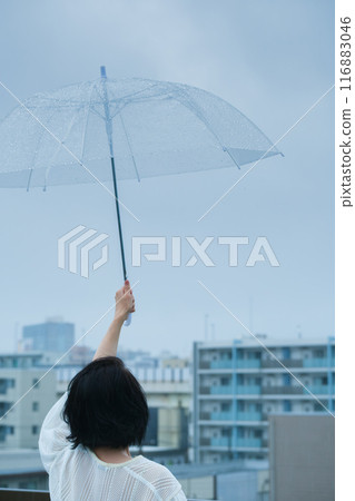 A middle-aged woman holding an umbrella in the pouring rain 116883046