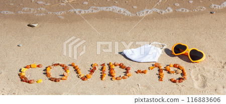 Inscription Covid-19 made of amber stones, protective mask and sunglasses on sand at beach Inscription Covid-19 made of amber stones, protective mask and sunglasses on sand at beach 116883606