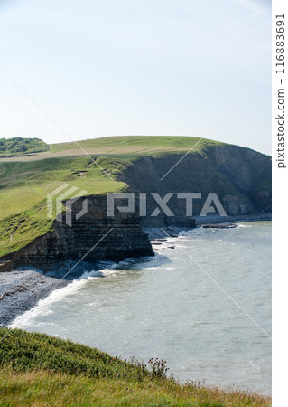 A coastline of gravel and a cove with cliffs formed by seawater erosion. On the outskirts of South Wales. 116883691