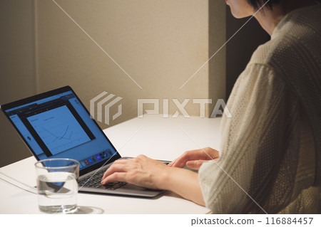 A middle-aged woman working at a computer at night A middle-aged woman working at a computer at night 116884457