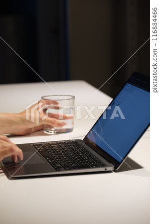 A middle-aged woman working at a computer at night A middle-aged woman working at a computer at night 116884466