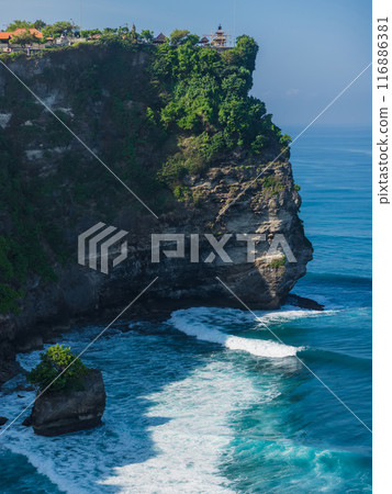 Touristic place and balinese temple. Scenic cliff with morning light and ocean with waves in Uluwatu, Bali. Touristic place and balinese temple. Scenic cliff with morning light and ocean with waves in Uluwatu, Bali. 116886381