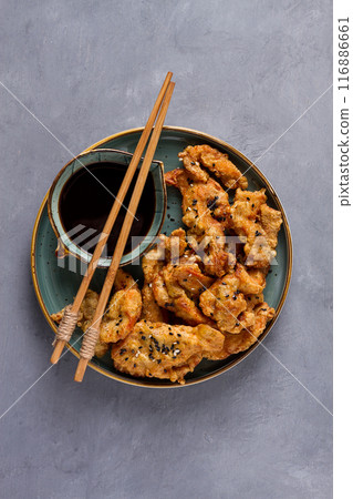 Fried meat in batter, deep-fried, with sesame seeds, and soy sauce, on a gray table, there are no people, Fried meat in batter, deep-fried, with sesame seeds, and soy sauce, on a gray table, there are no people, 116886661