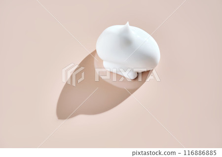 A smear of white cream on a beige background. 116886885