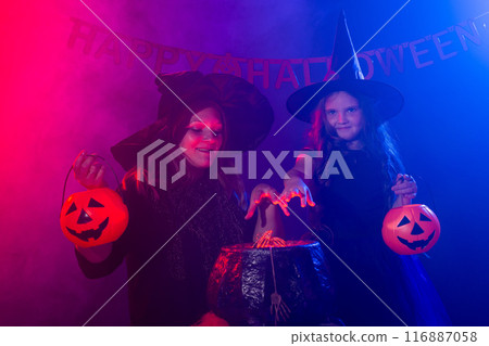 Two witches having fun together. Kid and mother conjure on magic pot. Halloween autumn holiday concept 116887058