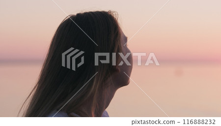 teenage girl standing on a beach at sunset teenage girl standing on a beach at sunset 116888232