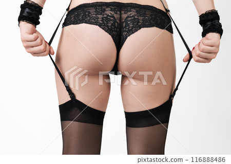 Close-up rear view of woman's legs and buttocks, wearing black panties and nylons. Sensational crop view of midsection of an unrecognizable female body, dressed in lingerie on white background 116888486