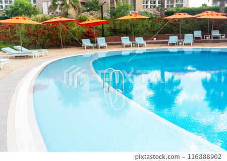 Step into a luxurious pool with a strip of coastal sand and brightly colored umbrellas and sun loungers Step into a luxurious pool with a strip of coastal sand and brightly colored umbrellas and sun loungers 116888902