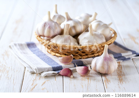 garlic bulbs in a basket on a wooden table, selective focus. 116889614