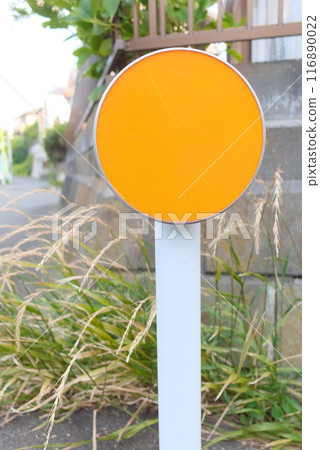 A large delineator installed in a rural area with vegetation. A large delineator installed in a rural area with vegetation. 116890022