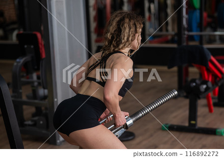 Middle-aged woman doing abdominal rows on a machine in the gym. Middle-aged woman doing abdominal rows on a machine in the gym. 116892272