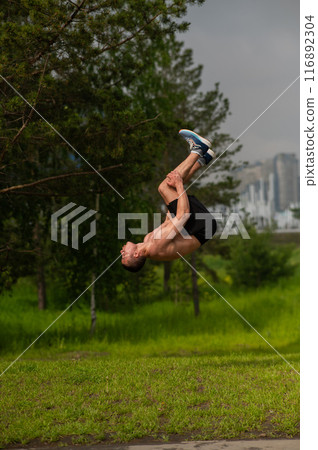 Young shirtless male athlete doing backflip on outdoors Vertical photo. Young shirtless male athlete doing backflip on outdoors Vertical photo. 116892304