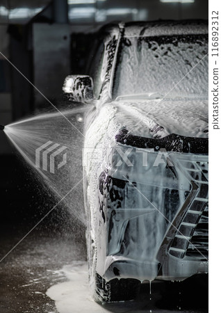 Man applying foam to black car in car wash. Vertical photo.  116892312