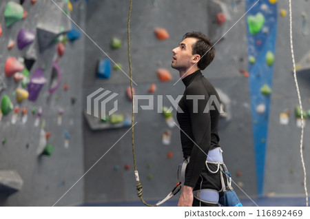 Caucasian man training on a climbing wall.  116892469