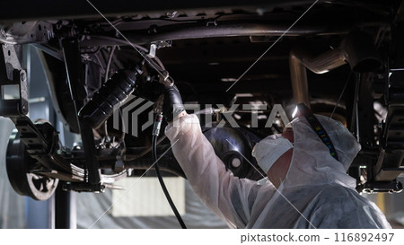 The master sprays an anti-corrosion compound on the bottom of the car. The master sprays an anti-corrosion compound on the bottom of the car. 116892497