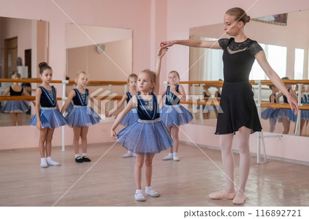 Children's ballet school. Caucasian woman teaching ballet to little girls. Children's ballet school. Caucasian woman teaching ballet to little girls. 116892721