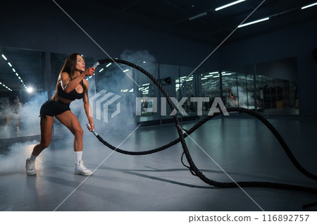 Caucasian woman doing exercise with ropes. Circuit training in the gym. Caucasian woman doing exercise with ropes. Circuit training in the gym. 116892757