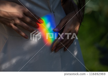 Faceless woman catching rainbow ray with her hands outdoors.  116892969