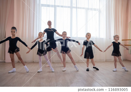 Children's ballet school. Caucasian woman teaching ballet to little girls. Children's ballet school. Caucasian woman teaching ballet to little girls. 116893005